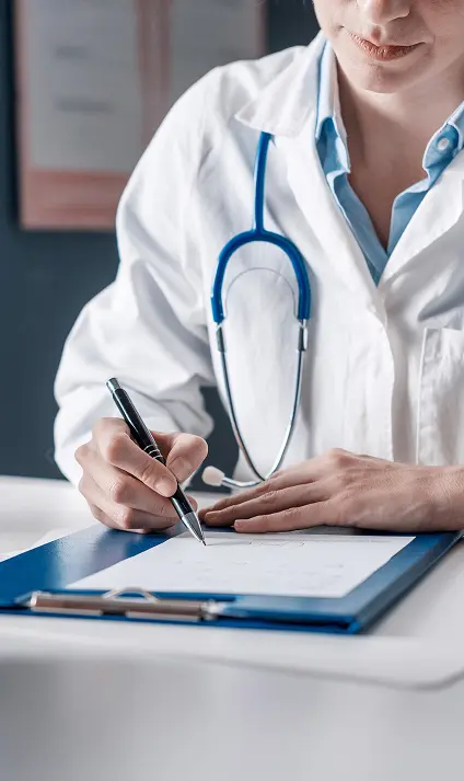 Médica de jaleco com estetoscópio escrevendo numa prancheta